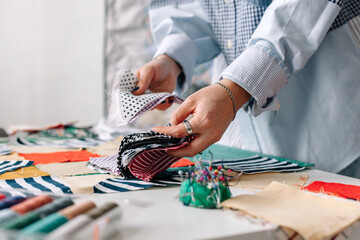 seamstress lays out pieces of various fabric on a work surface