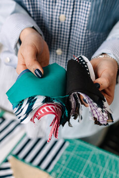 Crop woman seamstress showing pieces of various fabric 