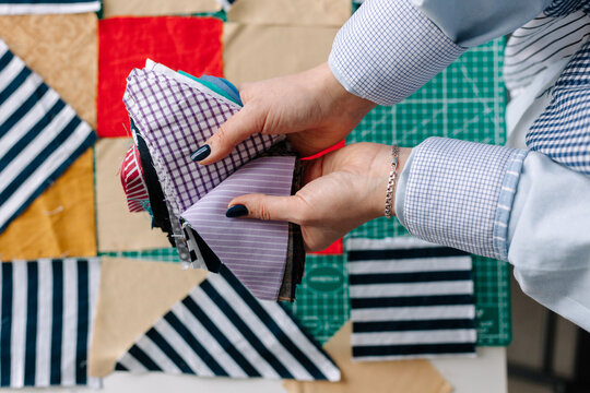 Crop woman seamstress showing pieces of various fabric. Patchwork. 