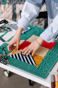 Young female patchwork artist selecting pieces of cloth in atelier. 