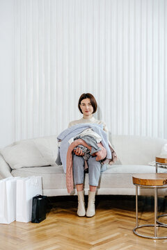Woman sitting with pile of clothes in arms on couch, direct flash