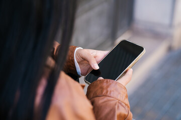 Unrecognizable lady browsing mobile phone on street