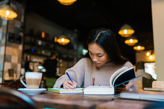 Focused Asian woman studying in cafeteria