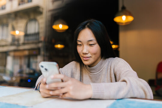 Content Asian woman checking messages on smartphone