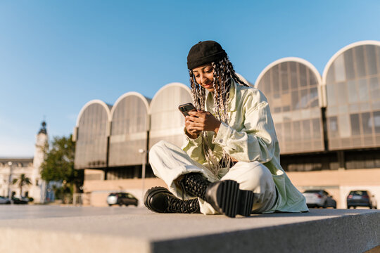 Stylish positive woman using cellphone in city