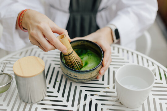 Crop woman mixing matcha tea