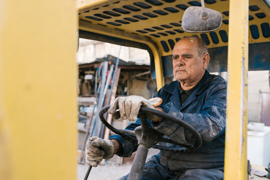 Senior workman shifting gears in forklift