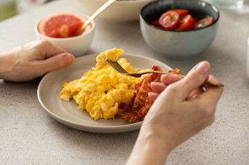 Person eating healthy breakfast - eggs with bacon