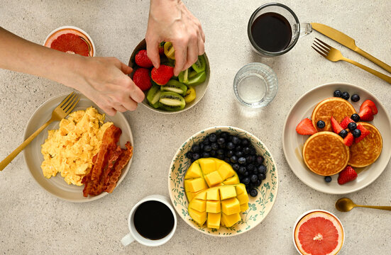 Woman eating fruits - strawberries - at breakfast. Served table.