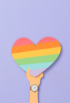Human hands holding heart with rainbow flag as a symbol