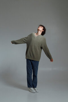 Carefree young man standing in gray studio