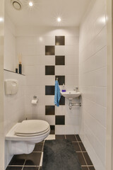 a small bathroom with black and white tiles on the walls, toilet, sink, and mirror in the corner