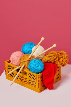 Clews of yarns with needles in basket on desk