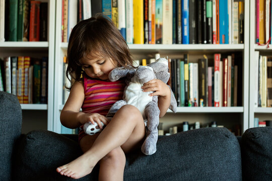 Brunet little girl with stuffed rabbit on sofa