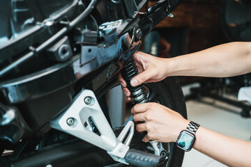 motorcycle mechanic check and Change rear Shock Absorbers motorcycle scooter at garage,motorcycle repair, maintenance and service concept © kasarp