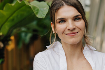 Optimistic woman near green plant