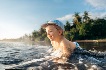 Boy plays in ocean waves at sunset.