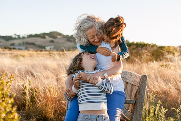 Grandmother and grandchildren embraced in golden california