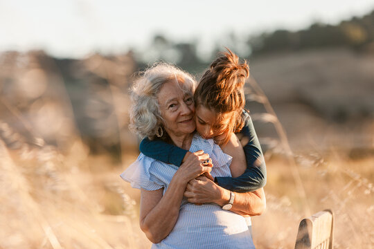 Senior woman and grandson hugging by the field
