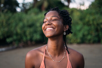 Peaceful black woman in bikini standing on beach