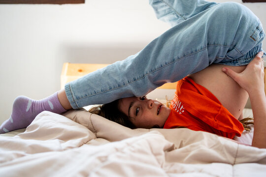  girl doing a somersault on the bed looking at camera