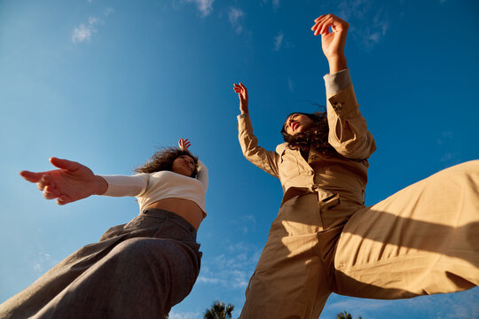 Stylish diverse ladies under cloudless blue sky