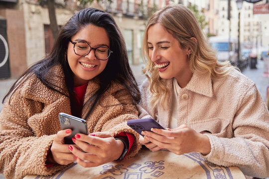 Female Friends Texting and Sharing on Mobile Phone. 