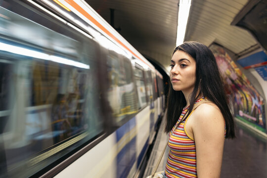 Young woman waiting for the train standing on the subway platform