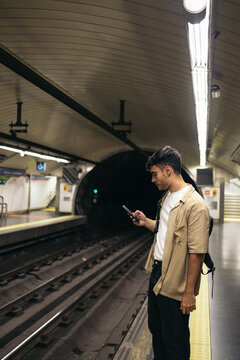 Young man waiting for the train standing on the subway platform