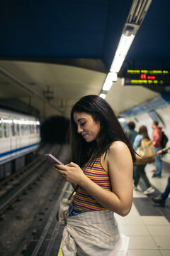 Young woman waiting for the train standing on the subway platform