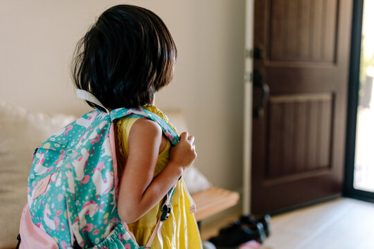 Little girl wearing a backpack, getting ready to go to school