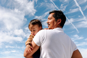 Loving asian father holding his infant son in his arms