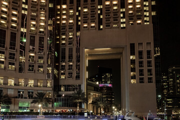 Night view from the promenade of Dubai Marina with illuminated skyscrapers, a water channel, yachts and ships in Dubai city, United Arab Emirates