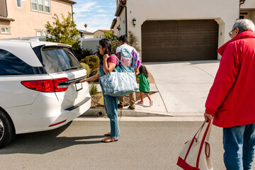 Family with grandparents packing the car with bags for a road trip