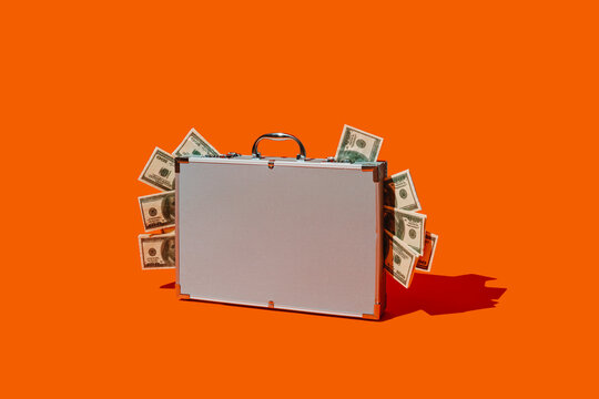 fake dollar banknotes peeking out of a metal briefcase