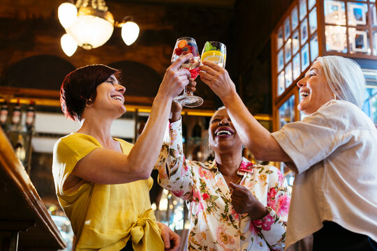 Cheerful women clinking glasses in cocktail bar
