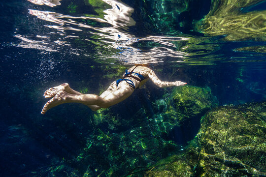 Woman Floating and Exploring Underwater in Cenote Tulum