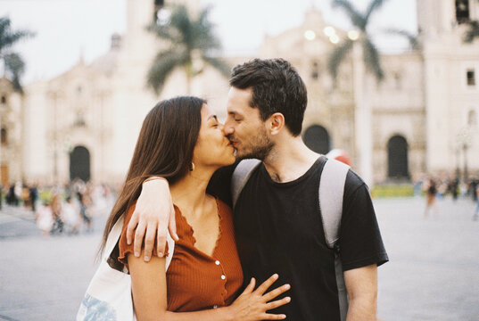 Analog picture of a couple kissing in front of a historical building