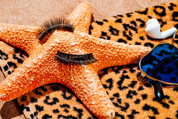 fake eylashes on a starfish, on a beach towel