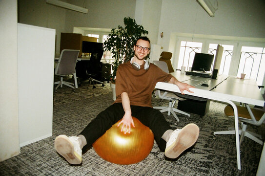 Film photo Young man sitting on a fitball in the office
