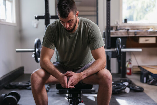 Tired, sweaty athlete resting in home workout space.