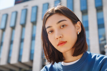 Young Asian female student sitting on street