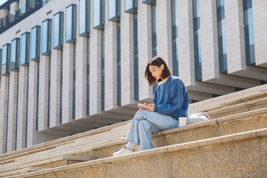 Asian student using smartphone near university