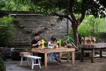 Asian mother and daughter coloring bird feeder painting