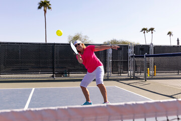 Senior Citizen Pickleball player looks to swing accurate  at ball 