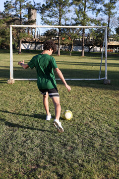 Athlete training gol kicks alone in the soccer field  