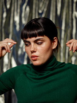 Serious woman snapping fingers and whistling against party backdrop 