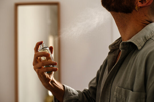 Man spraying perfume to his neck