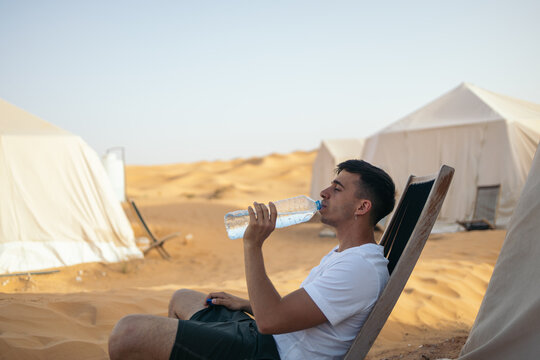 Young traveler drinking water in the desert