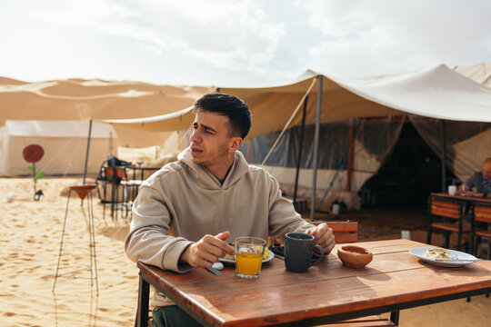 Traveler man eating in a tent camp in the Sahara desert
